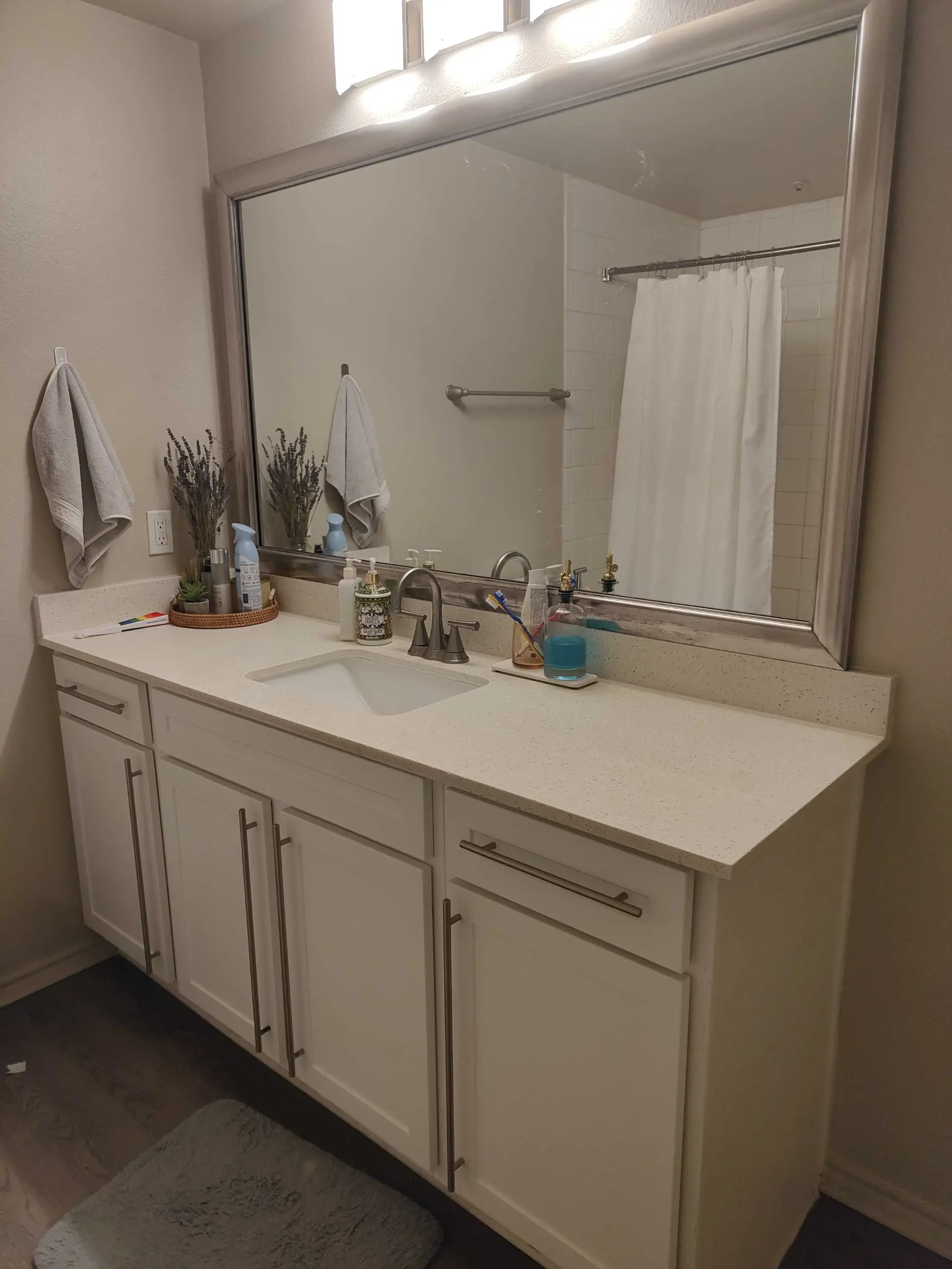 <p>Create an image of a contemporary bathroom approximately 5 feet by 8 feet in size. This bathroom features a sleek, floating vanity with integrated LED lighting shining from beneath. Above this vanity, picture a frameless mirror with a backlit LED border. To the right side of the room, there is a walk-in shower, complete with crystal clear glass doors and a cascading rainfall showerhead. The once existing laminate flooring has been switched out for large-format marble tiles. Soft, neutral wall colors contribute to the overall calming atmosphere of the space, perfectly complemented by modern fixtures with a brushed nickel finish.</p>