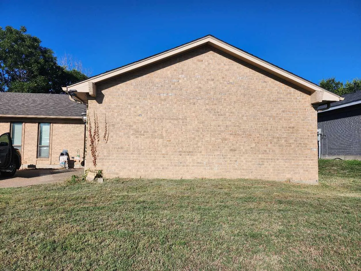 <p>Create a detailed image of a farmhouse-style house exterior that measures approximately 20 feet wide by 15 feet tall. The house is enhanced with charming rustic features, such as a stone pathway that leads to a newly constructed wooden porch with a pitched roof. Large windows on the house are adorned with wooden shutters, and climbing plants grace the brick walls. The house is nestled in a verdant environment, encircled by a small garden teeming with a variety of colorful flowers and lush greenery. Above the picturesque scene, the sky is resplendently clear and a brilliant shade of blue.</p>