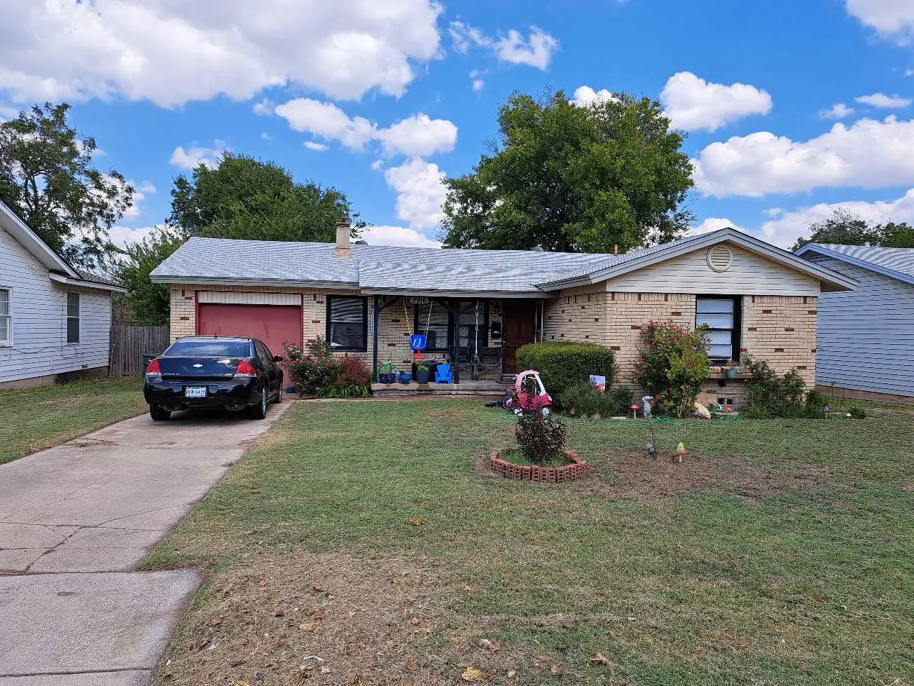 <p>Generate an image of a modernized exterior of a single-story suburban house. The house features a garage on the left side and neutral-toned horizontal siding with vertical wooden accents near the entrance. The front yard is composed of a minimalist garden with a quaint sitting area paved with attractive pavers, leading to a newly constructed wooden porch. The driveway shows off an expanded, sleek concrete finish with a small path of stepping stones connecting it to the front porch. The dimensions of the house are approximately 40 feet in width and 25 feet in depth.</p>