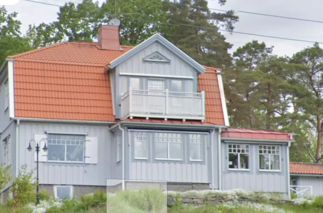 <p>Create an image of a traditional Scandinavian-style home that has been modernized. The facade of the house should be light grey with contrasting white trims, replacing what was previously blue. The roof should be made from sleek, modern material but should hold onto its warm terracotta tone. The balcony should be expanded and feature comfortable outdoor seating and planters. Large, energy-efficient windows are to replace smaller old windows, allowing more natural light into the house. The landscape around the house should be lush with well-trimmed greenery and a cobblestone pathway leading to the entrance. The facade should measure approximately 25 feet in width and 20 feet in height.</p>